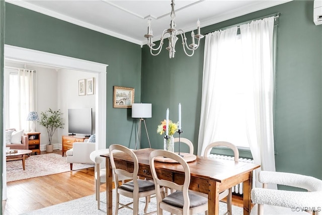 dining space featuring crown molding, baseboards, a wall unit AC, light wood-style flooring, and an inviting chandelier