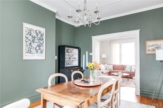 dining area with a notable chandelier, wood finished floors, and crown molding