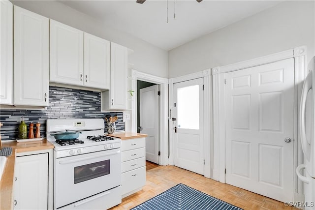 kitchen with decorative backsplash, white cabinets, white gas stove, and freestanding refrigerator