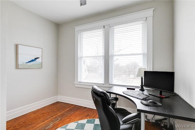 office space with baseboards, a healthy amount of sunlight, and wood finished floors