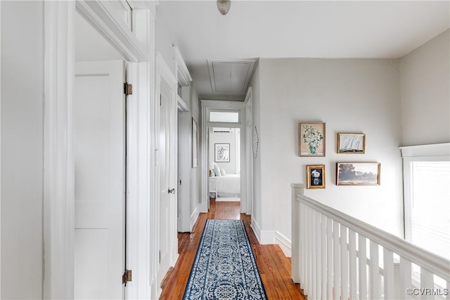 corridor featuring attic access, baseboards, and wood finished floors