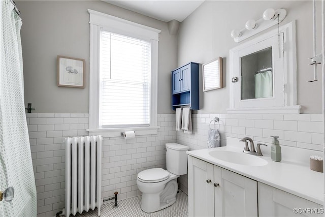 bathroom with vanity, radiator, tile patterned floors, toilet, and tile walls