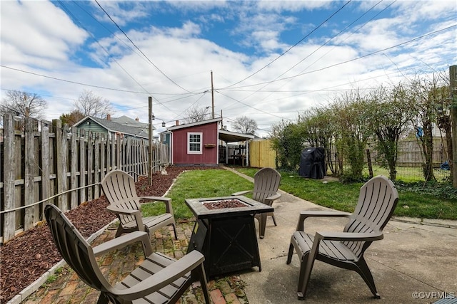 view of patio with an outdoor structure, a fenced backyard, a storage shed, and an outdoor fire pit