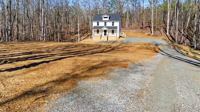 view of front of house featuring gravel driveway and a forest view