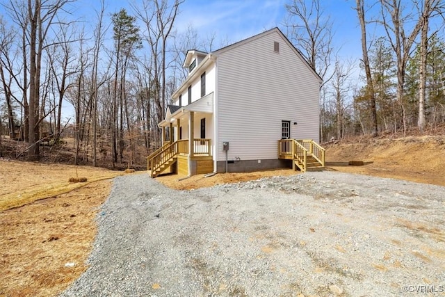 view of side of home featuring gravel driveway and crawl space