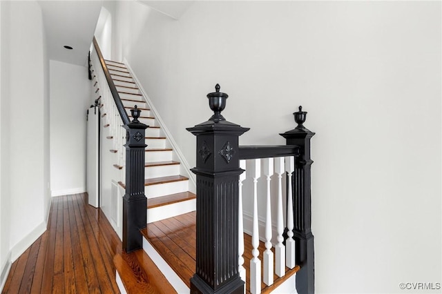 staircase featuring hardwood / wood-style floors and baseboards