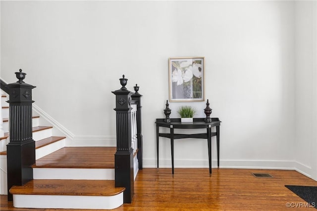 stairs with wood finished floors, visible vents, and baseboards