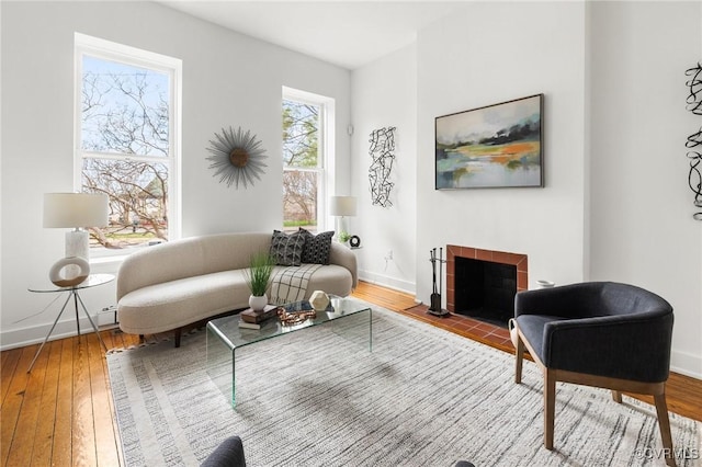 living area featuring a tiled fireplace, hardwood / wood-style floors, and baseboards