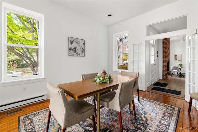 dining space with a baseboard heating unit, hardwood / wood-style flooring, visible vents, and french doors