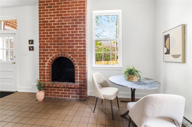 interior space featuring a wealth of natural light, light tile patterned floors, baseboards, and a brick fireplace
