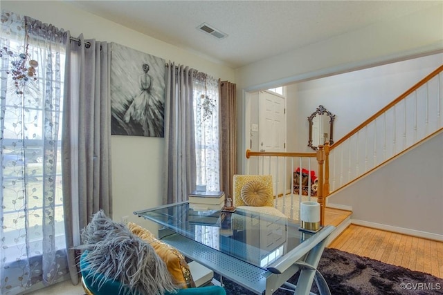 dining area featuring visible vents, baseboards, wood finished floors, and stairs