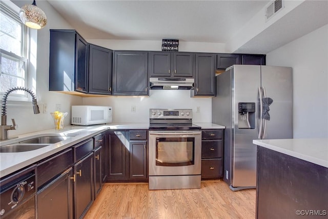 kitchen featuring visible vents, light wood-style flooring, under cabinet range hood, a sink, and stainless steel appliances