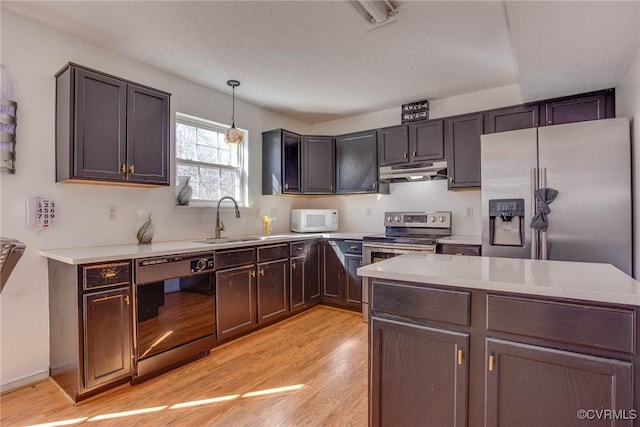 kitchen with light countertops, light wood-style floors, under cabinet range hood, and stainless steel appliances