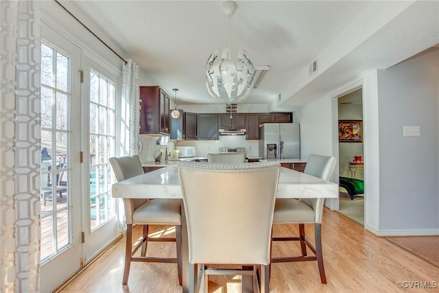 dining space with visible vents, baseboards, light wood-style flooring, and a chandelier