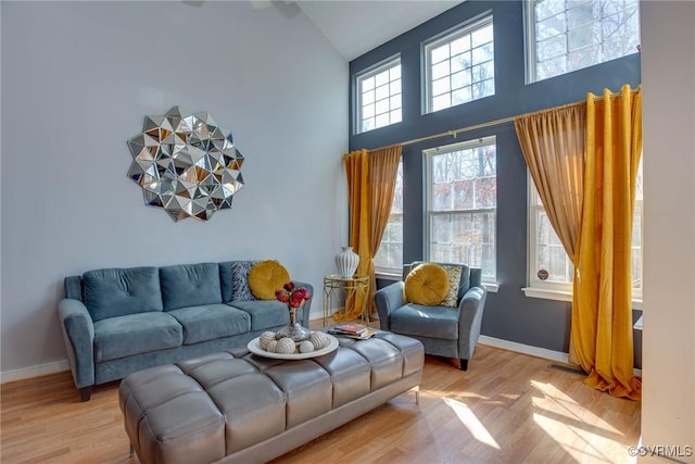 living room featuring wood finished floors, baseboards, and a towering ceiling