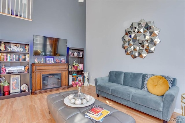 living room featuring baseboards, wood finished floors, and a glass covered fireplace