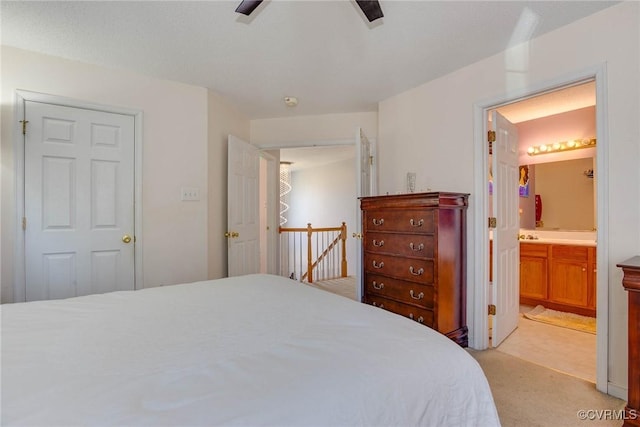 bedroom with ceiling fan, light colored carpet, and ensuite bath