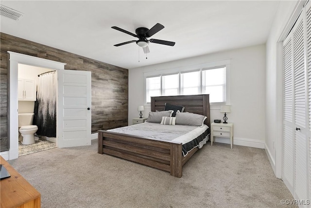 bedroom featuring visible vents, ensuite bath, a closet, carpet, and wooden walls