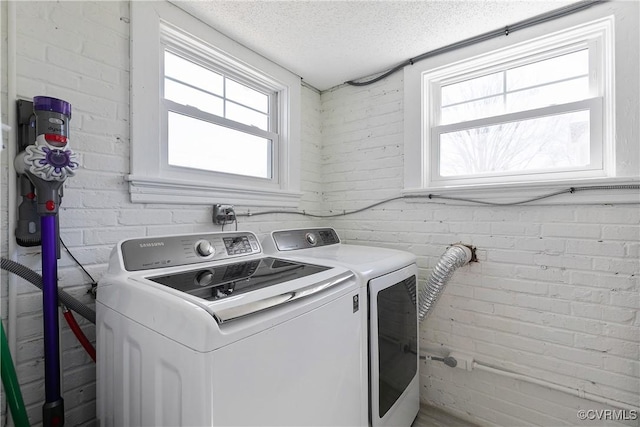 clothes washing area featuring laundry area, independent washer and dryer, a wealth of natural light, and a textured ceiling