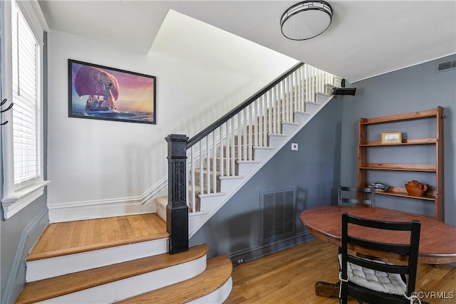 stairs featuring visible vents, baseboards, a healthy amount of sunlight, and hardwood / wood-style floors