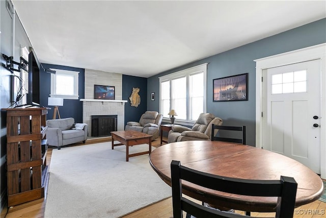 dining area with a wealth of natural light, light wood finished floors, and a brick fireplace