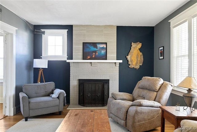 living room with a brick fireplace and wood finished floors