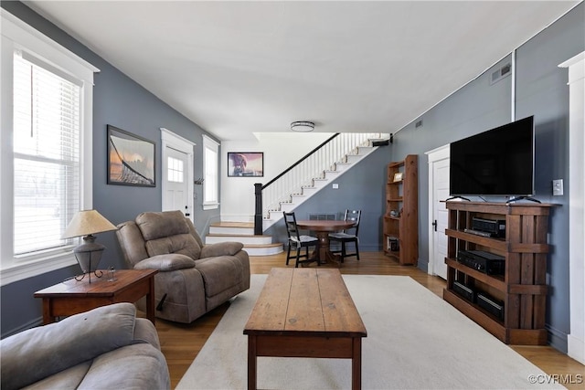 living room with stairway, baseboards, visible vents, and wood finished floors