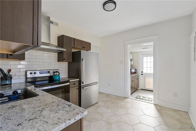 kitchen with backsplash, wall chimney range hood, light stone countertops, dark brown cabinetry, and appliances with stainless steel finishes