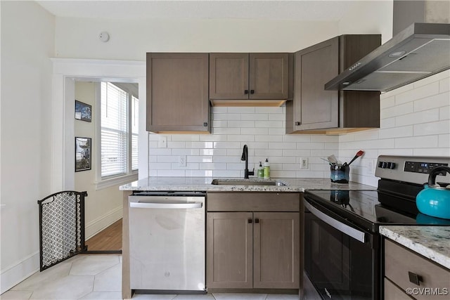 kitchen featuring a sink, tasteful backsplash, stainless steel appliances, wall chimney exhaust hood, and light stone countertops