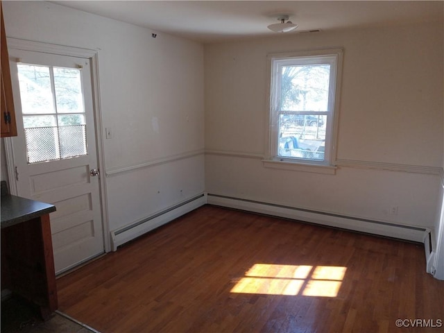 unfurnished room featuring baseboard heating and wood finished floors