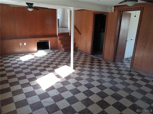 interior space with wooden walls, stairs, and a ceiling fan