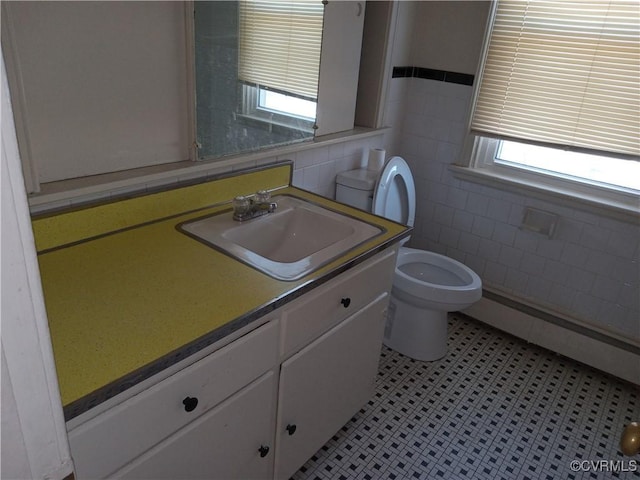 half bathroom featuring toilet, tile walls, and vanity