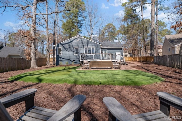 back of house with a deck, a fenced backyard, a lawn, and a chimney