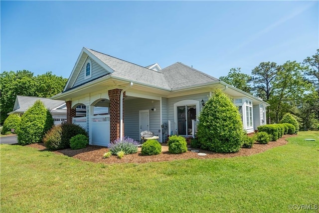 view of front of house featuring brick siding, an attached garage, a shingled roof, and a front lawn