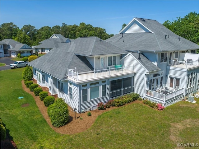 back of property featuring a yard, a balcony, and a shingled roof