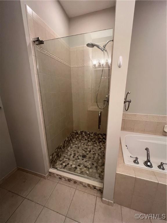 bathroom featuring baseboards, a stall shower, tile patterned flooring, and a bath