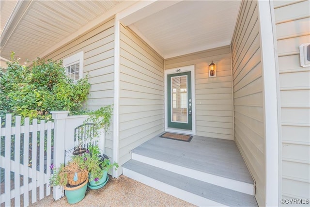 view of exterior entry featuring a garage and fence