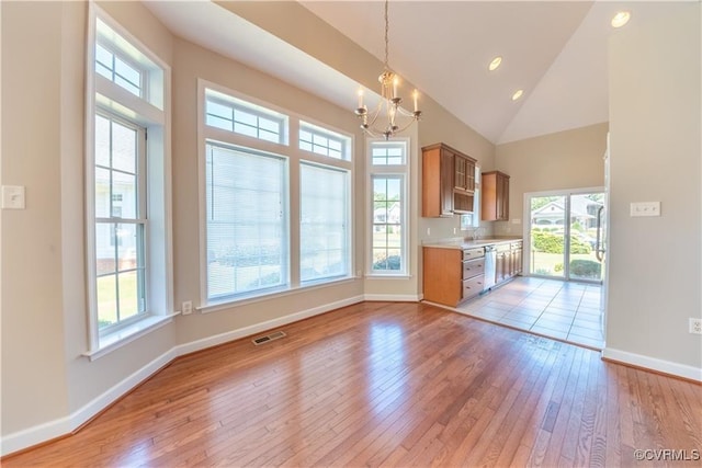 kitchen with light wood finished floors, visible vents, baseboards, light countertops, and high vaulted ceiling