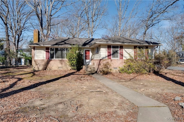 view of front of home with a chimney, brick siding, and crawl space