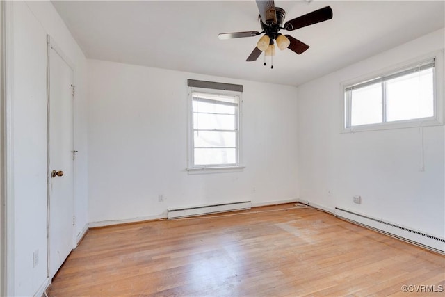 empty room featuring light wood-style floors, a baseboard radiator, plenty of natural light, and baseboard heating