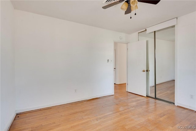 unfurnished bedroom with a closet, light wood-style flooring, a ceiling fan, and baseboards