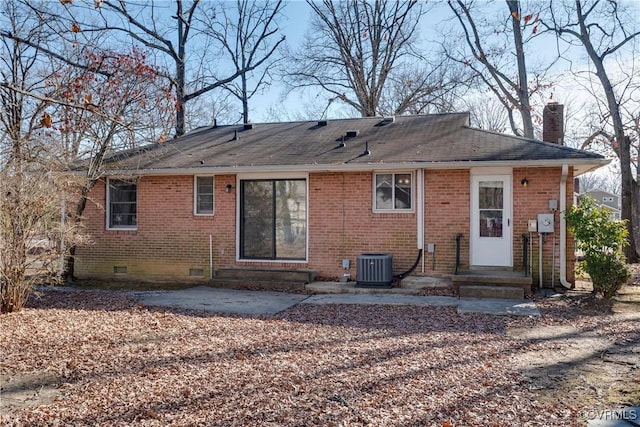 rear view of property with brick siding, crawl space, cooling unit, and a chimney