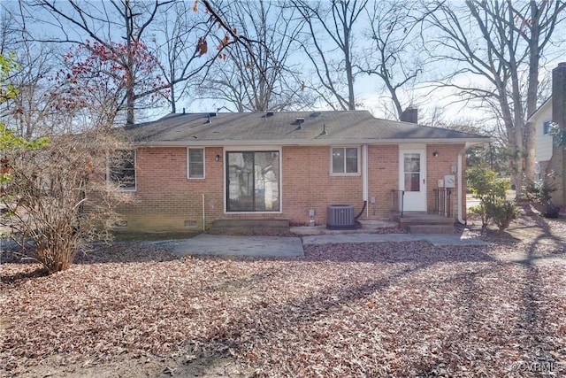 rear view of house with crawl space, brick siding, central AC, and a chimney