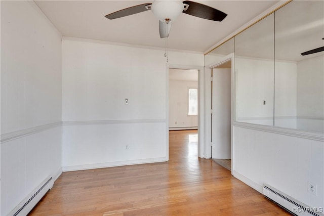 spare room with light wood-type flooring, a baseboard heating unit, and a ceiling fan