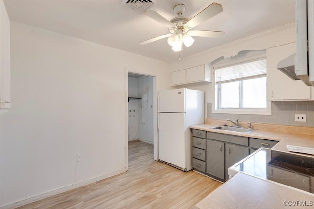 kitchen with visible vents, a sink, tasteful backsplash, freestanding refrigerator, and light wood-style floors