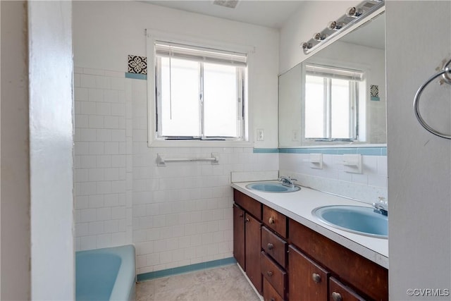 full bath featuring tile walls, double vanity, a wainscoted wall, and a sink