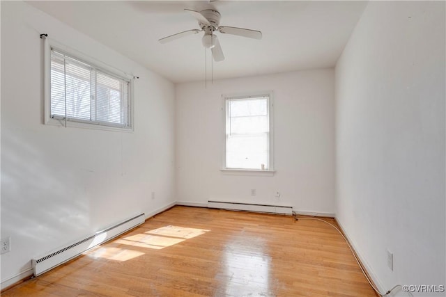 spare room with a baseboard heating unit, baseboards, a ceiling fan, and light wood finished floors