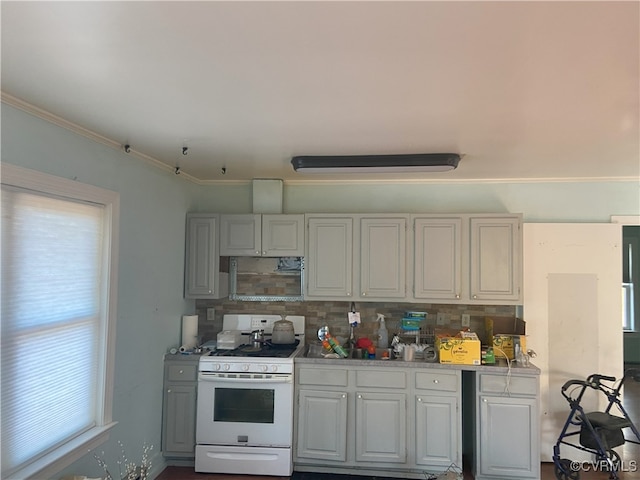 kitchen with white range with gas cooktop, backsplash, light countertops, and ornamental molding