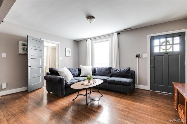 living room featuring a wealth of natural light, dark wood-type flooring, and baseboards