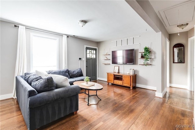 living room with baseboards, attic access, and wood finished floors